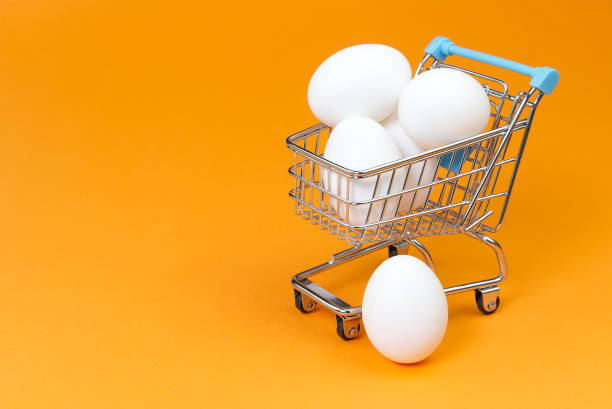 istock chicken white eggs in a shopping cart. isolated on orange 1215029282