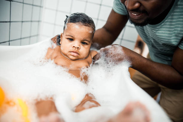 istock Smiling father bathing cute newborn daughter in bathroom 1215033448