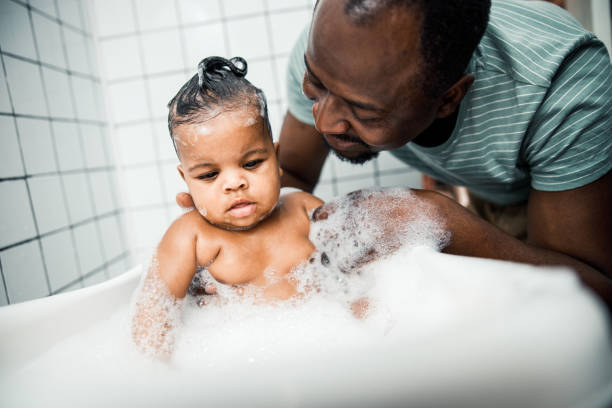 istock Smiling father bathing cute newborn child at home 1215037781