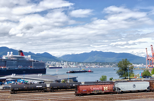 Vancouver, Canada - June 10, 2019: View of West Coast Express Railroad and Cruise ship near Canada Place. North Vancouver surrounded by mountains in the background