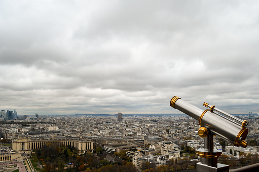 View of the city of Paris from the Eiffel tower on a cloudy day.  focus on the one binocular they the tower.