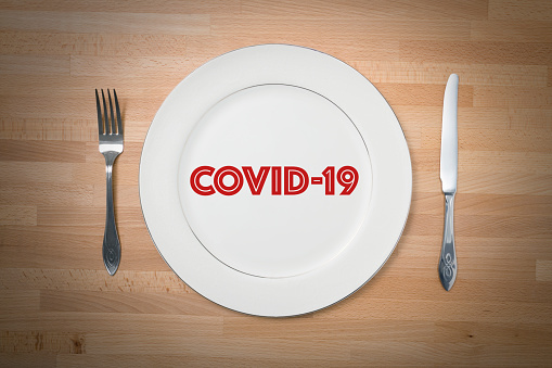 White plate with fork and knife on the table during quarantine. Coronavirus.