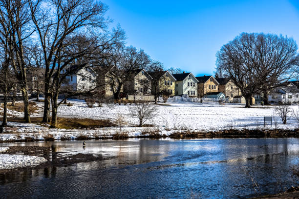 A view of Weasel Brook Park in Clifton, New Jersey during the winter with the brook crossing through the park behind a white wooden fence. Clifton in one of the townships that conform Passaic County in New Jersey.