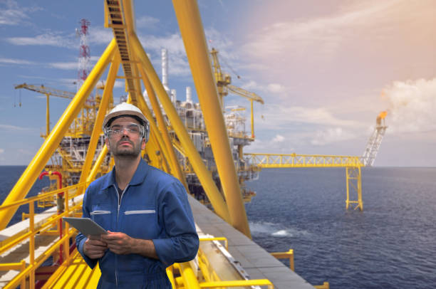 istock Caucasian man engineer staff worker with tablet in hand and offshore rig background concept. 1215049824