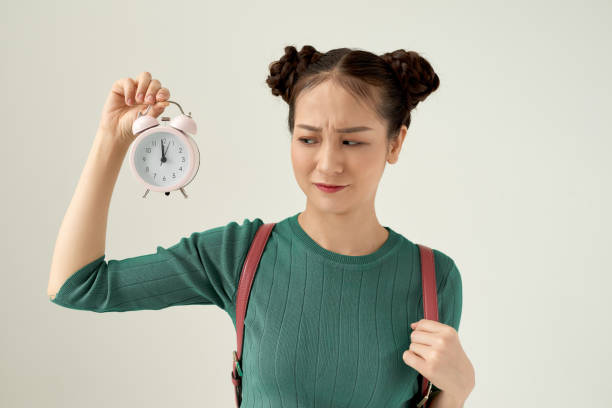 istock young pretty woman feeling puzzled and confused, with a dumb, stunned expression looking at something unexpected holding an alarm clock. 1215052785
