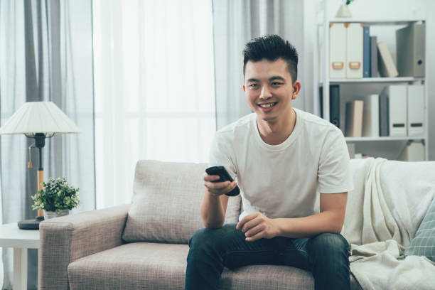 istock young asian chinese man holding remote control 1215055676