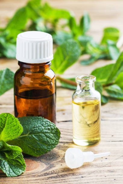 istock Essential aroma oil with peppermint on wooden background. Selective focus, copy space. 1215061995