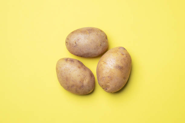 istock Raw potato tubers on a yellow background. 1215066502