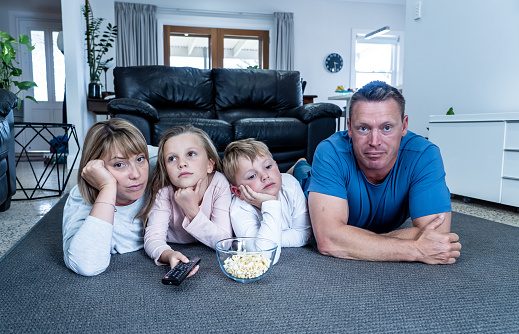 Coronavirus lockdow. Bored family watching tv helpless in isolation at home during quarantine COVID 19 Outbreak. Mandatory lockdowns and self isolation recommendations forces families stay home.
