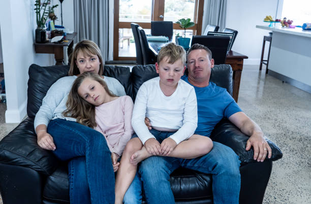 istock Coronavirus lockdow. Bored family watching tv helpless in isolation at home during quarantine COVID 19 Outbreak. Mandatory lockdowns and self isolation recommendations forces families stay home. 1215067140