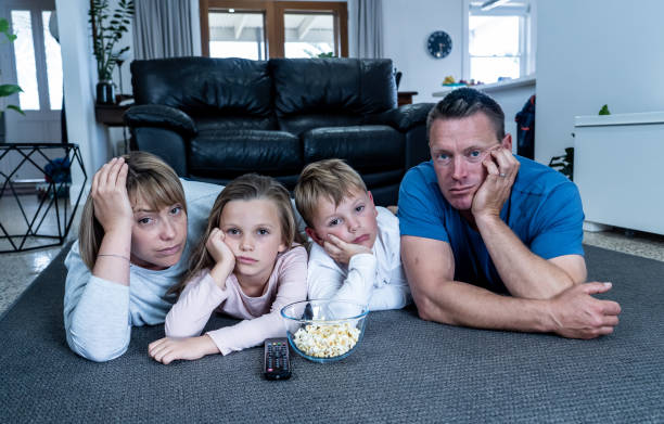 Coronavirus lockdow. Bored family watching tv helpless in isolation at home during quarantine COVID 19 Outbreak. Mandatory lockdowns and self isolation recommendations forces families stay home. coronavirus lockdow. familia aburrida viendo la televisión indefensa en aislamiento en casa durante la cuarentena covid 19 brote. los bloqueos obligatorios y las recomendaciones de autoaislamiento obligan a las familias a permanecer en casa.