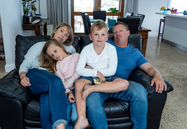 istock Coronavirus lockdow. Bored family watching tv helpless in isolation at home during quarantine COVID 19 Outbreak. Mandatory lockdowns and self isolation recommendations forces families stay home. 1215067146
