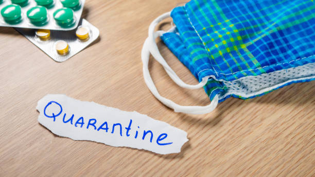 istock Quarantine inscription on paper with face mask and pills 1215067363