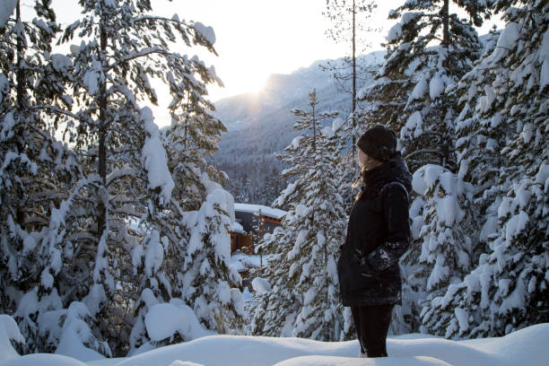 istock Young woman walks along snowy forest path towards sunrise view 1215069255