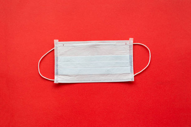 istock disposable medical mask red background. close up 1215070067