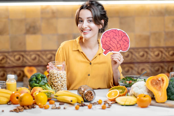 Human brain model and variety of healthy fresh food Woman holding human brain model with variety of healthy fresh food on the table. Concept of balanced nutrition for brain health food recall stock pictures, royalty-free photos & images