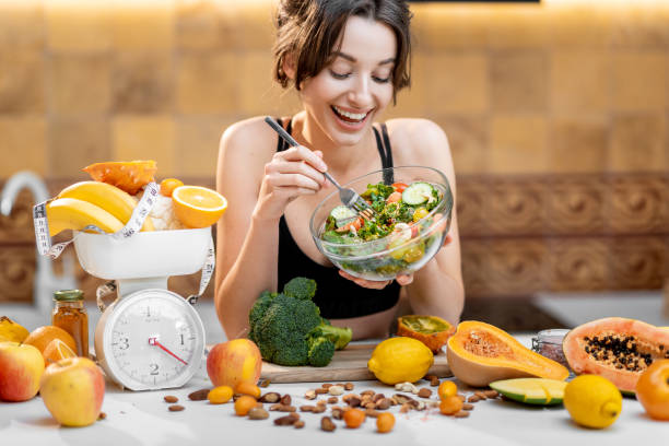 mujer deportiva con comida saludable en la cocina - consumption scale fotografías e imágenes de stock