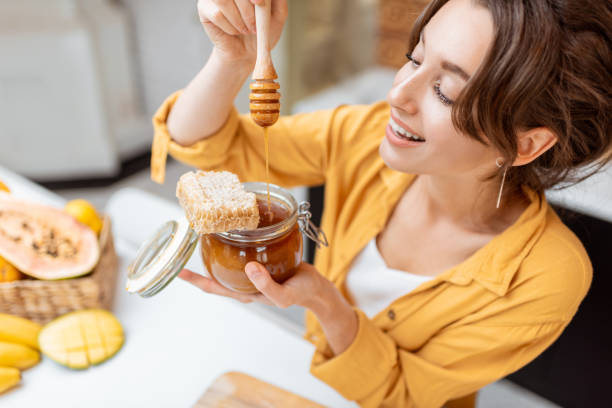istock Woman eating honey at home 1215073532
