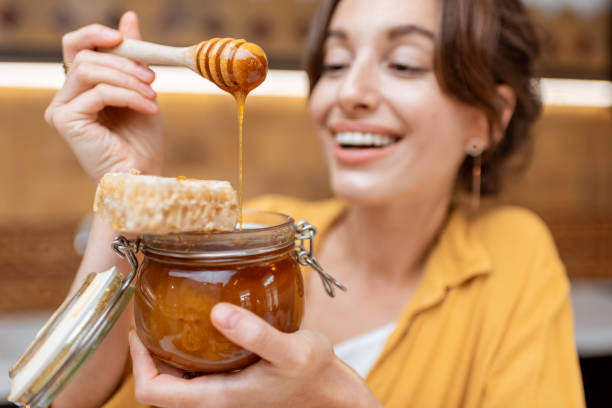 istock Woman eating honey at home 1215073539