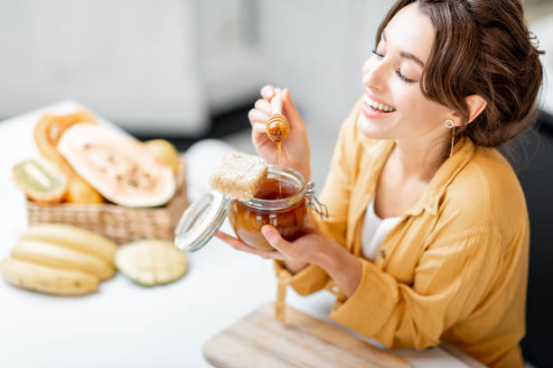 istock Woman eating honey at home 1215073547