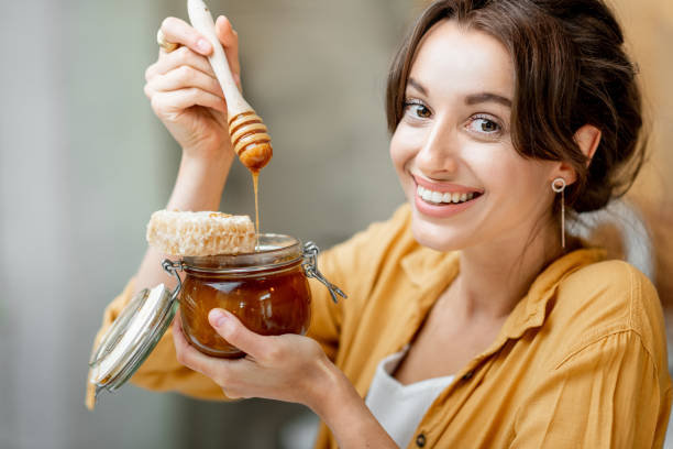 istock Woman eating honey at home 1215073549