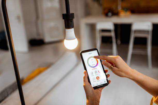 Controlling light bulb with mobile device Controlling light bulb temperature and intensity with a smartphone application. Concept of a smart home and managing light with mobile devices led stock pictures, royalty-free photos & images