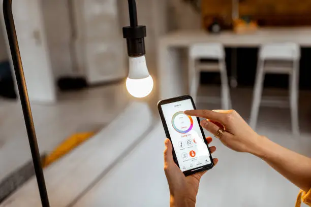 Controlling light bulb temperature and intensity with a smartphone application. Concept of a smart home and managing light with mobile devices