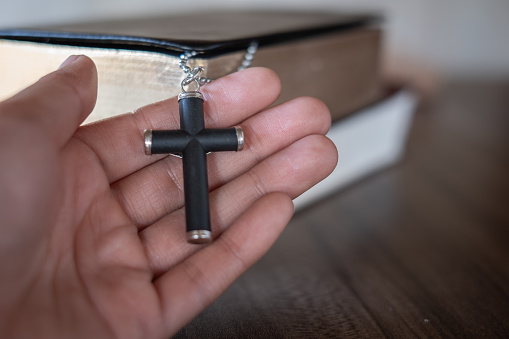 The crucifix lay on the palm of the hand,Bible background And close-up images of praying for the blessing of Jesus, God. Faith in the sacred power of God through prayer to Him, Christianity, Jesus.