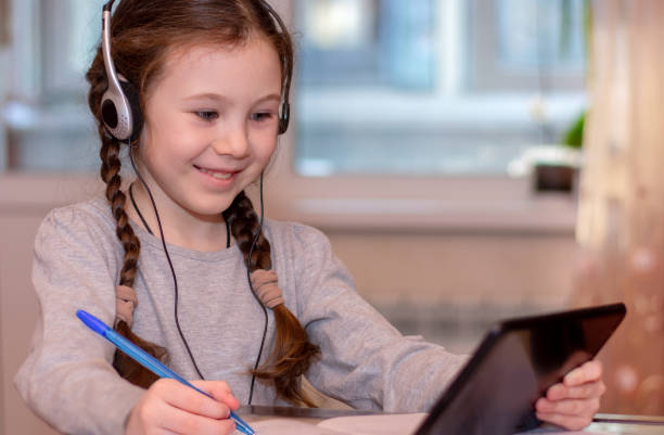 szczęśliwa uczennica pisząc na tablecie i odrabiająca pracę domową. odległość szkoły domowej. edukacja online - happy kid audio zdjęcia i obrazy z banku zdjęć