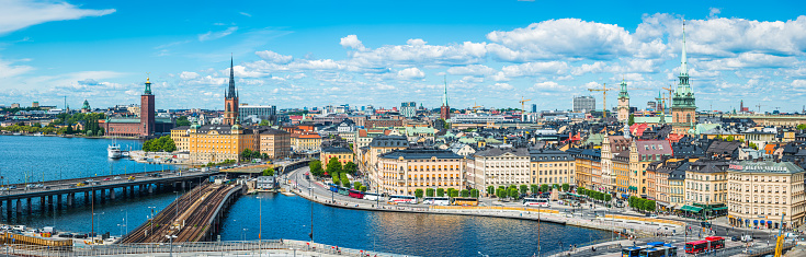 Blue summer skies framing the landmarks of Stockholm, Sweden's vibrant capital city, from the iconic bell tower of City Hall to the historic townhouses, restaurants and bars of Gamla Stan.