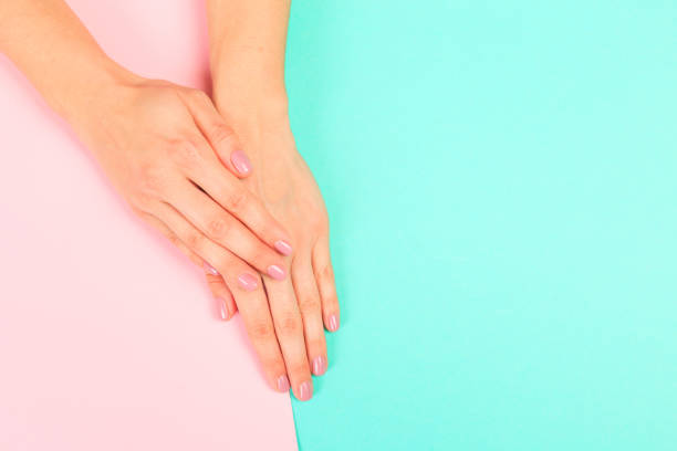 istock female  manicure. Beautiful young woman's hands on pastel   background 1215079177