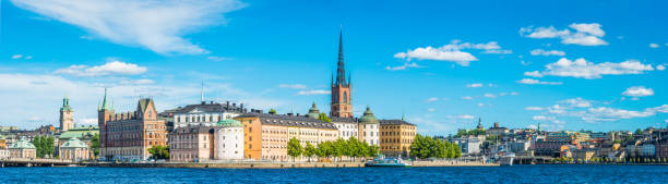 Stockholm Gamla Stan blue harbour waterfront panorama Riddarholmen Sodermalm Sweden Panoramic view over the blue waters of Riddarfjarden to the historic waterfront of Gamla Stan and Sodermalm beneath the blue skies and white fluffy clouds of a sunny summer afternoon in the heart of Stockholm, Sweden's vibrant capital city. sodermalm photos stock pictures, royalty-free photos & images