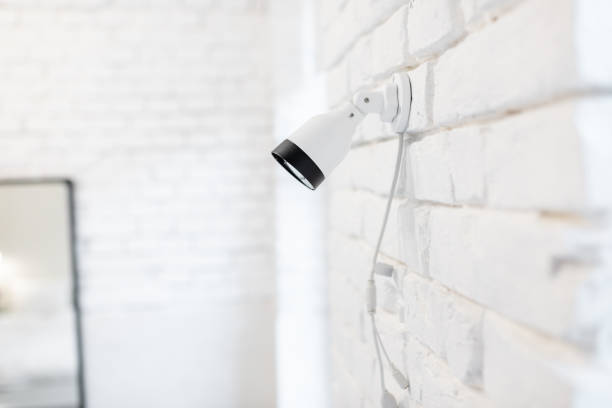 istock Camera mounted on the white brick wall indoors 1215080639