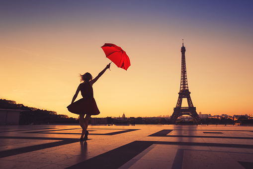 travel to Paris, silhouette of happy woman with red umbrella near Eiffel Tower