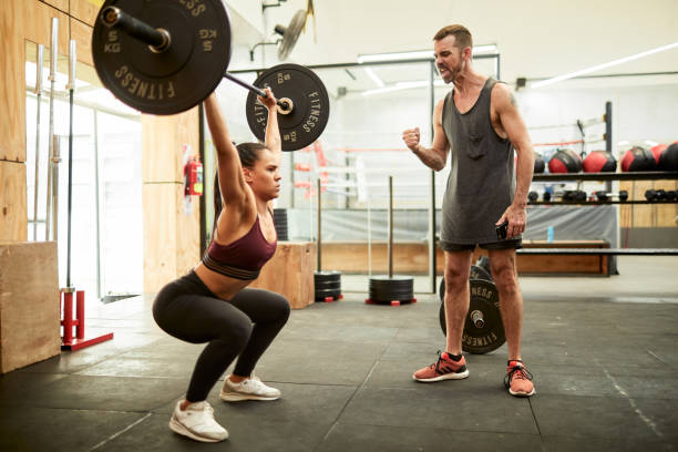 istock A cross-training instructor is cheering a woman lifting weights. 1215082832