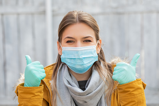 Portrait of a young woman wearing surgical mask and gloves because of coronavirus pandemic alert