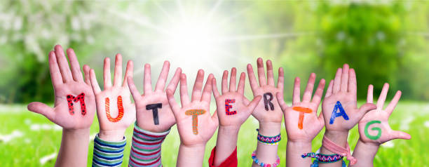 istock Children Hands Building Word Muttertag Means Mother Day, Grass Meadow 1215085508