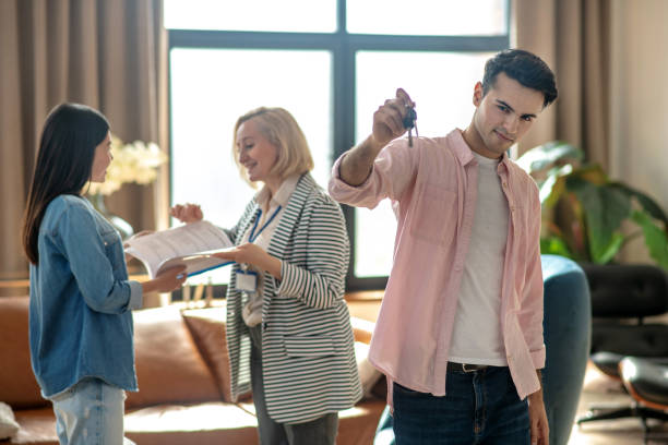 istock Dark-haired tall man showing the keys in his hand and looking contented 1215086819