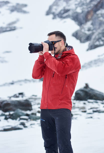 istock Young man taking picture in winter mountains. 1215088406