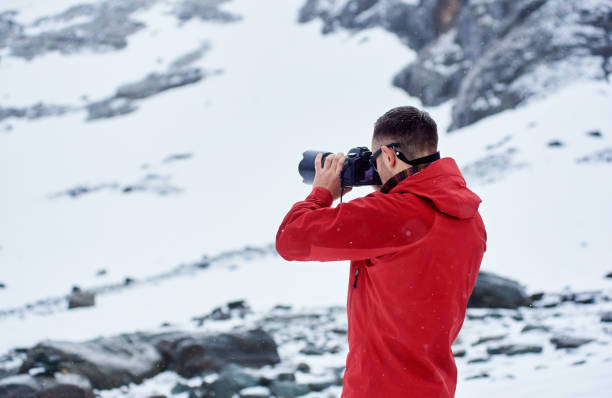 istock Young man taking picture in winter mountains. 1215088505