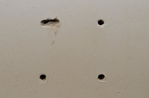 Three round and one uneven holes in the wall close-up