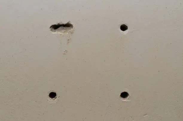 Three round and one uneven holes in the wall close-up