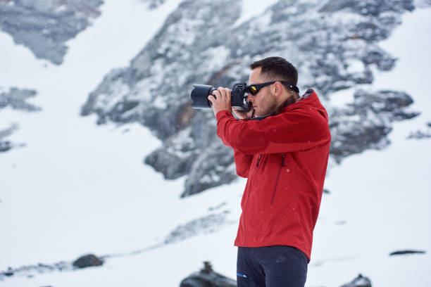 istock Young man taking picture in winter mountains. 1215088859