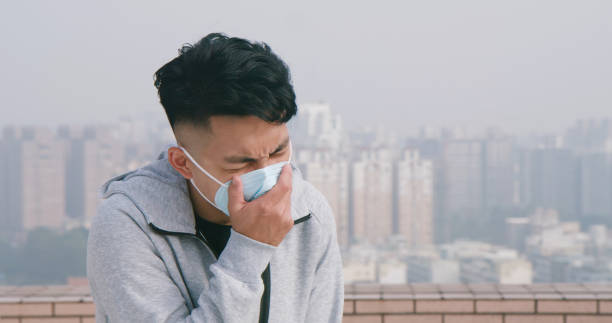istock man coughs and wears mask 1215088875