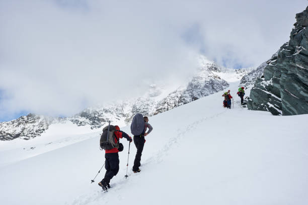istock Group of hikers climbing the hill covered with snow. 1215088910