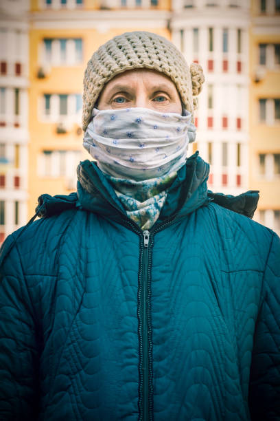 A poor elderly woman wears a homemade mask to protect herself from viruses stock photo