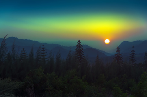 Landscape of beautiful colorful dramatic sunset sky, twilight sky over silhouette mountains and pine forest.