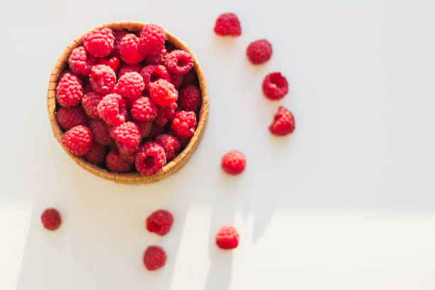 Tasty raspberries in wooden jar on white background