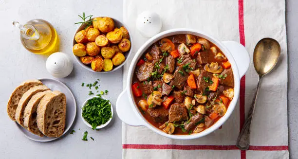 Photo of Beef bourguignon stew with vegetables. Grey background. Top view.