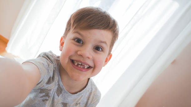 istock Funny small boy taking selfies and grimacing. Smiling cute boy taking photos and facetime chatting. 1215095276